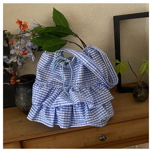 Detail view of blue gingham tote bag featuring tiered ruffles and light blue drawstring closure
