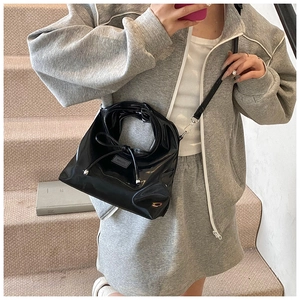 Detail of black patent leather handbag with bow and high-gloss mirror finish texture