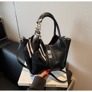 Detail of black crocodile texture bucket bag with silver clasp and silk scarf handle decor