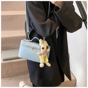 Detail of light blue lychee pattern leather handbag with cute plush puppy charm
