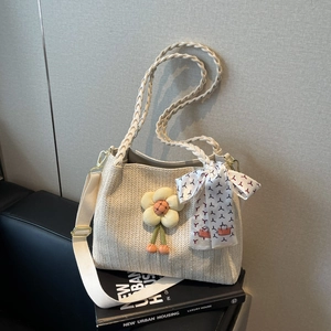 Dettaglio della borsa tote in paglia beige con ciondolo a fiore e foulard geometrico