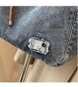 Macro shot of blue denim tote bag with silver metal plate and braided rope handle