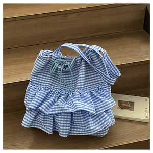 Detail of blue and white gingham tote bag with ruffled hem and drawstring closure
