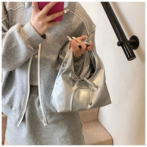 Detail of silver metallic hobo bag featuring a decorative bow and small metal logo