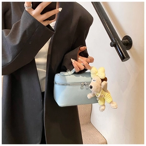 Detail of light blue pebble leather vanity bag with cute plush puppy charm