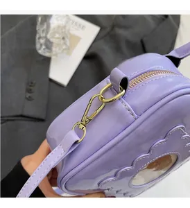 Close-up of light purple patent leather bag with gold hardware and bear detail