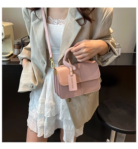 Detail of pink vintage square bag with woven texture, metal hook, and fashion tag charm