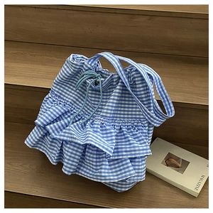 Blue and white checkered tote bag with tiered ruffle layers and drawstring closure on stairs