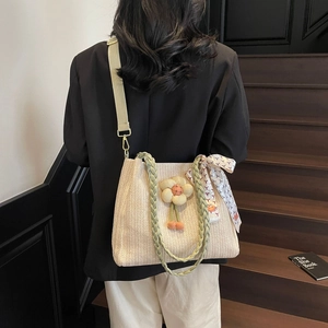Dettaglio della borsa tote in paglia beige con manici verdi e ciondolo in seta colorata