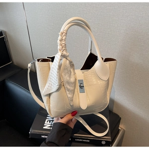 Detail of cream crocodile embossed handbag with silver clasp and checkered silk scarf handle
