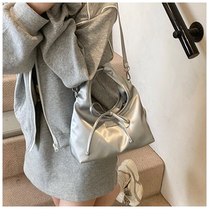 Close-up of metallic silver handbag featuring drawstring bow and slim shoulder strap