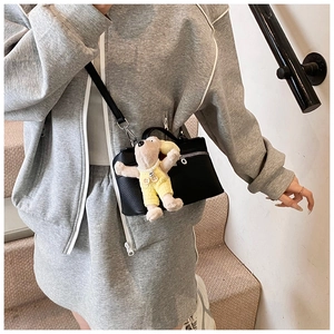 Close-up of black lychee grain mini box bag with cute yellow dog plush charm