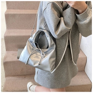 Detail of silver metallic handbag with bow drawstring and adjustable shoulder strap