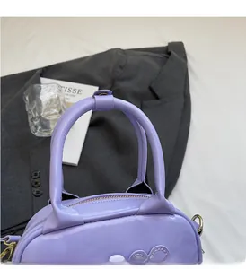 Detail of light purple glossy leather handbag showing handle and heart stitched texture