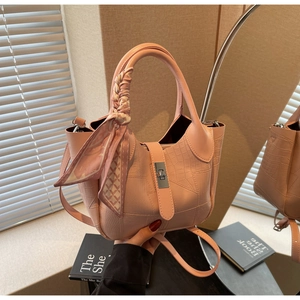 Detailed view of pink croc-embossed leather bucket bag with silk scarf handle and silver lock