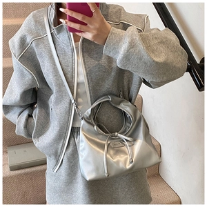 Detail of silver metallic bucket bag with a stylish bow knot and slim shoulder strap