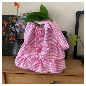 Detail view of pink gingham drawstring bag with layered ruffle design on wooden desk