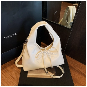 Detail of creamy white bucket bag with soft drawstring bow and detachable shoulder strap