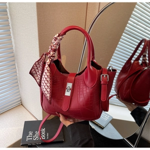 Detail of red croc-embossed bucket bag with silk scarf and silver twist lock closure