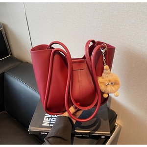 Detail of red leather tote bag with pleated design and creative plush charm accessory