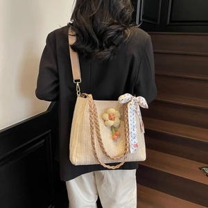 Dettaglio della borsa tote in paglia intrecciata con decoro girasole e foulard di seta