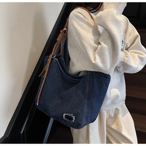 Close-up of deep blue denim tote bag featuring braided rope straps and metal ring details