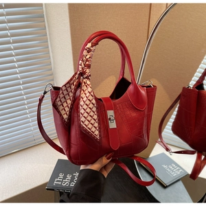 Detail of red croc-effect handbag with silver twist lock and decorative silk scarf