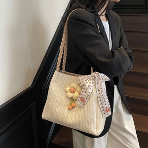 Dettaglio macro della borsa tote intrecciata beige con tracolla intrecciata e fiore
