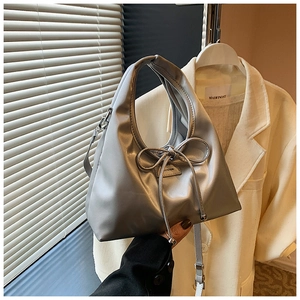 Close-up of metallic silver handbag with a large decorative bow and branding detail