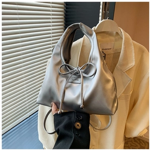 Close-up of a silver metallic handbag featuring a minimalist bow tie design and glossy finish