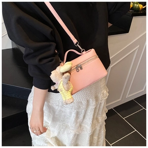 Pink textured leather mini handbag with cute teddy bear charm shown on a model