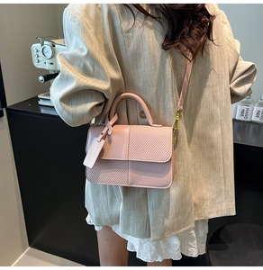 Detail of pink PU crossbody bag with contrast weave texture and fashion hangtag