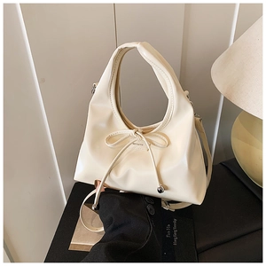 Detail of cream white PU leather bucket bag featuring a bow and NO FILTER label