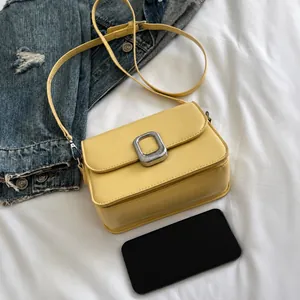 Detail of yellow rectangular crossbody bag with silver square buckle and textured leather