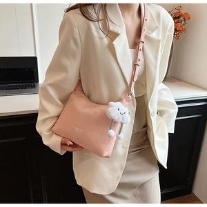 Detail of light pink PU leather crossbody bag featuring a plush cloud charm and bow buckle