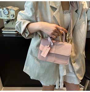 Detail of pink checkerboard textured crossbody bag with gold hardware and fashion tag