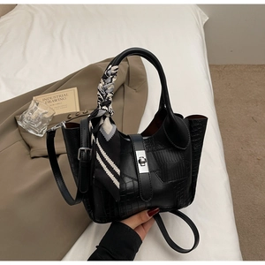 Detail of black faux leather bucket bag with silver twist lock and decorative silk scarf