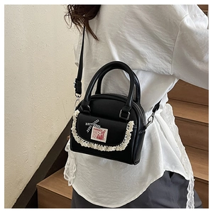 Close-up of black PU shell bag with lace pocket and plaid bow detail on model