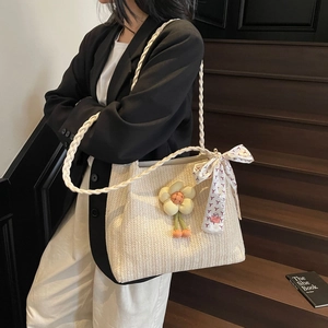 Dettaglio borsa tote in paglia intrecciata con ciondolo a girasole e foulard di seta