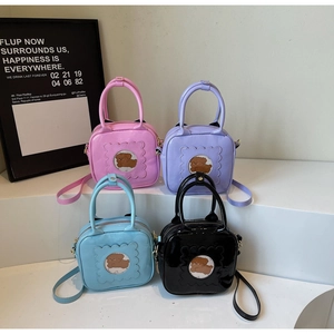 Detail of square patent leather mini bags with round bear window and wave trim
