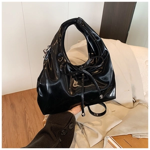 Detailed close-up of high-gloss black leather handbag with chic bow and metallic charm
