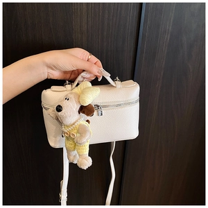 Detailed view of white litchi pattern handbag with a cute plush dog charm and long strap