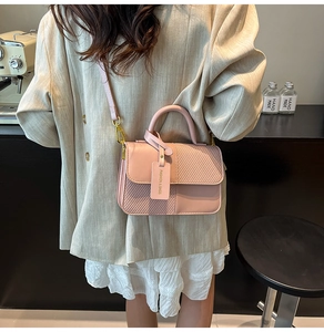 Pink patchwork handbag with woven texture detail worn by a model in a minimal studio