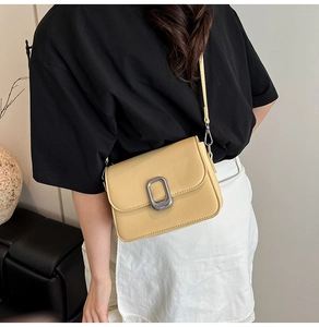 Chic beige square crossbody bag with silver metal buckle on a fashion model shoulder