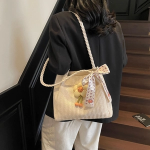 Dettaglio borsa shopper in paglia con decorazioni floreali e sciarpa sulla spalla