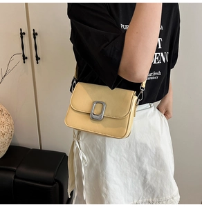 Model wearing a yellow leather square bag with silver buckle and crossbody strap
