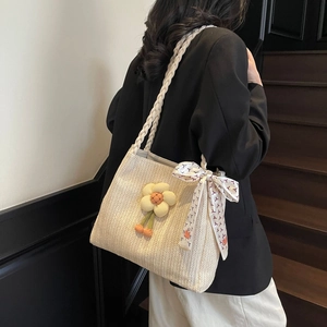 Dettaglio borsa shopper in paglia intrecciata con ciondolo a fiore e foulard