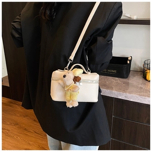 Cream lychee leather crossbody bag with a cute plush dog charm on a black blazer
