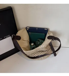 Interno spazioso di una grande borsa in paglia intrecciata con tablet e accessori