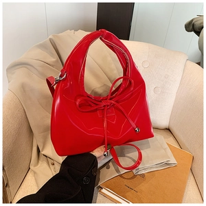 Detailed close-up of glossy red patent leather handbag with silver sphere metal charms